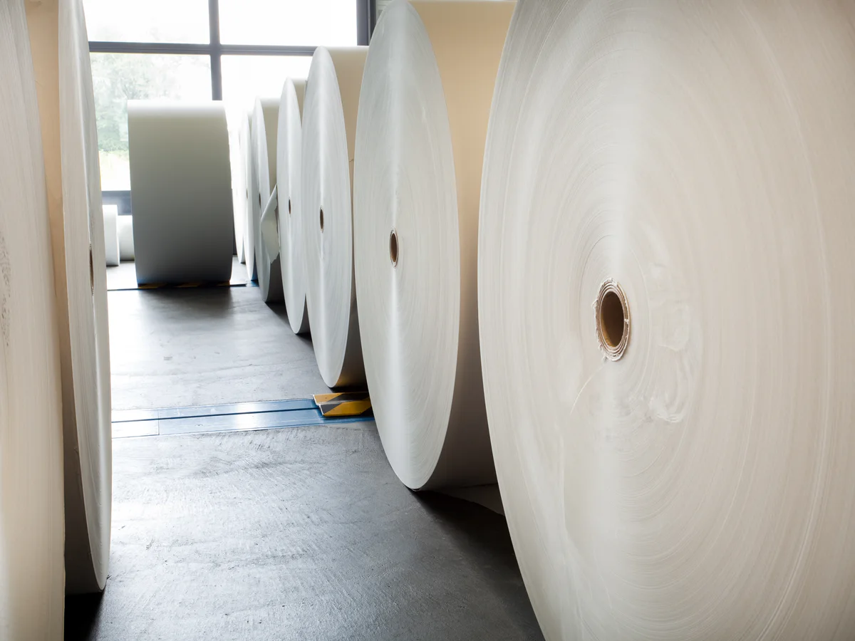 Allée entre des bobines de papier blanc dans un dépôt INTERPAP